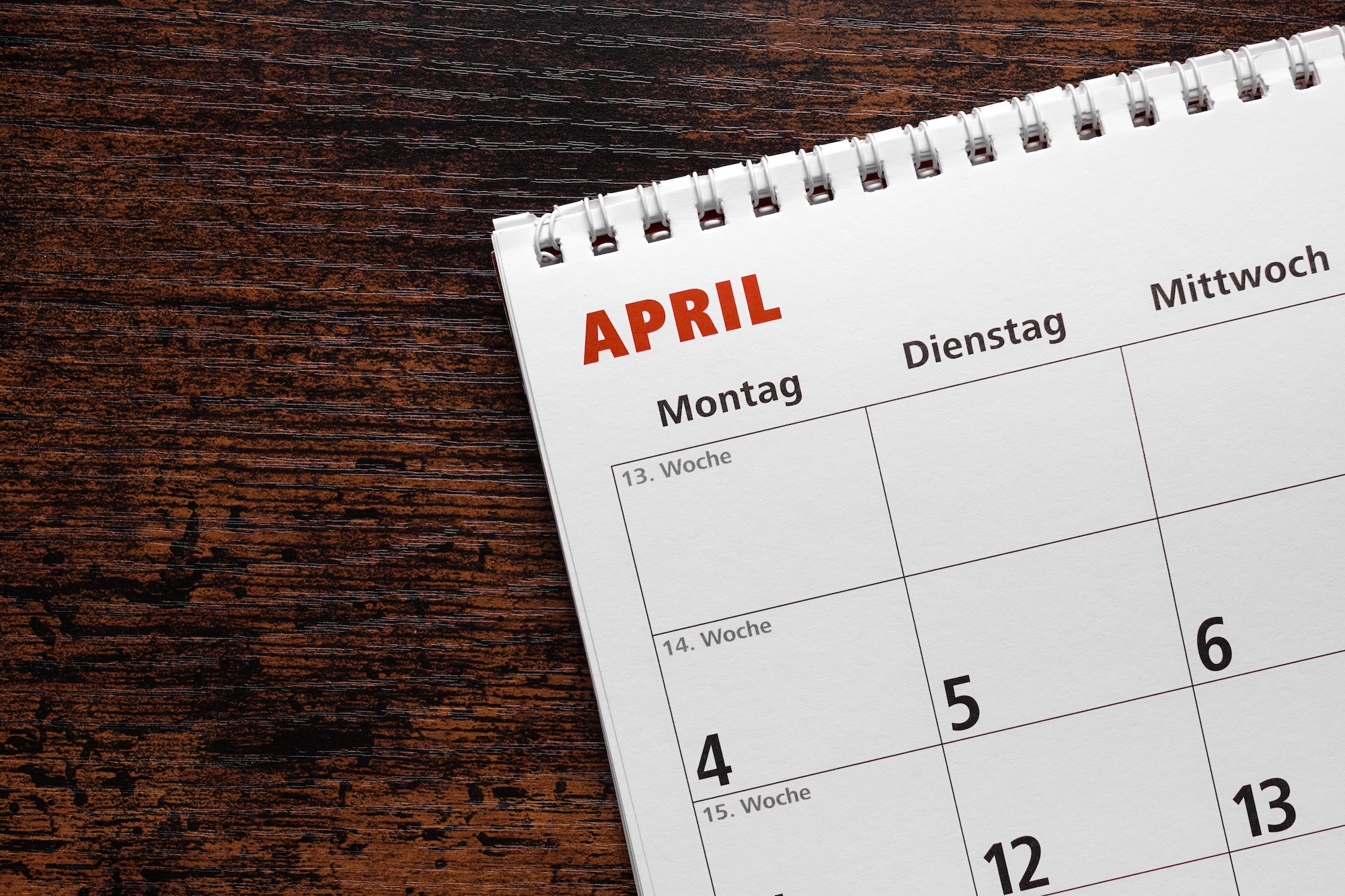 month of april in german calendar or planner on wooden desk background with copy space